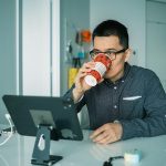 Man drinkt koffie achter computerscherm