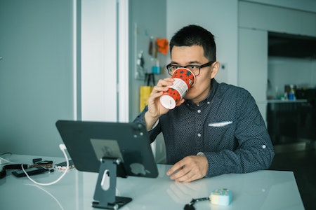 Man drinkt koffie achter computerscherm